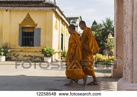 Two young monks walking into Wat Kandal after their work blessing the businesses; Battambang, Cambodia View Large Photo Image Stock Photo - Two young monks walking into Wat Kandal after their work blessing the businesses; Battambang, Cambodia. Fotosearch