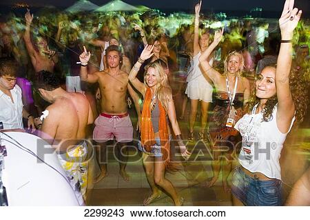 Stock Image - UAE, Abu Dhabi, Festival revellers dancing around pool at night Coma festival; Al Maya Island. Fotosearch