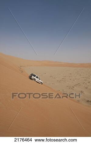 Picture - UAE, Abu Dhabi, Four wheel drive going down steep sand dune; Liwa. Fotosearch