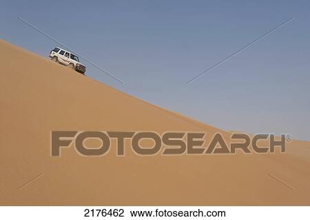 Stock Image - UAE, Abu Dhabi, Four wheel drive going down steep sand dune; Liwa. Fotosearch