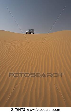 Stock Image - UAE, Abu Dhabi, Four wheel drive going across sand dunes; Liwa. Fotosearch