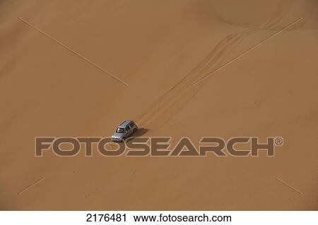 Stock Image - UAE, Abu Dhabi, Four wheel drive going down steep sand dune; Liwa. Fotosearch