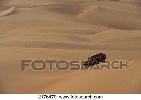 Stock Photo - UAE, Abu Dhabi, Four wheel drive going across sand dunes; Liwa. Fotosearch
