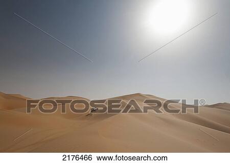 Stock Photograph - UAE, Abu Dhabi, Four wheel drive going across sand dunes; Liwa. Fotosearch