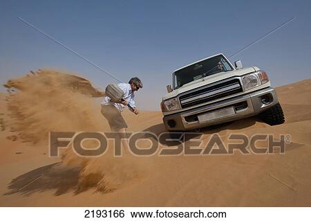 UAE, Abu Dhabi, Man trying to dig out 4 wheel drive stuck in soft sand; Liwa View Large Photo Image Stock Photograph - UAE, Abu Dhabi, Man trying to dig out 4 wheel drive stuck in soft sand; Liwa. Fotosearch