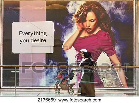 Stock Photo - UAE, Arab family walking past sign in the Dubai Mall shopping centre; Dubai. Fotosearch