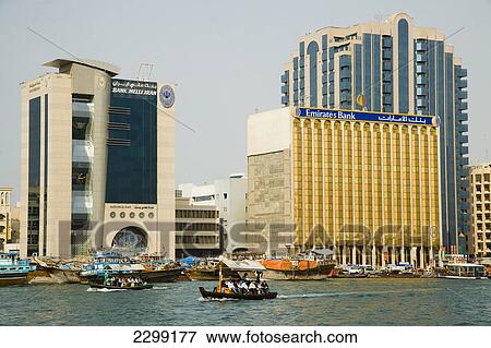 Stock Photo - UAE, Bussling waterway traffic of Dubai Creek. Small ferries and fishing boats and private vessels crossing narrow waterway in Dubais centre. High Rise corporate buildings donimate the waterside skyline; Dubai. Fotosearch