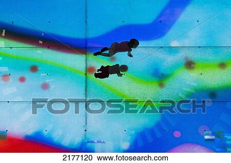Stock Image - UAE, Dubai Mall shopping centre; Dubai, Looking down on two young children on illuminated LED floor. Fotosearch