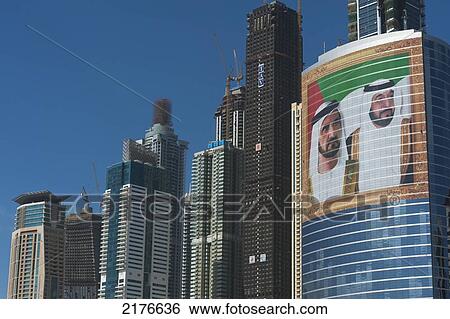 Stock Photograph - UAE, Large portrait of Sheikh Mohammed Bin Rashid Al Maktoum and Khalifa bin Zayed Al Nahyan on office building; Dubai. Fotosearch