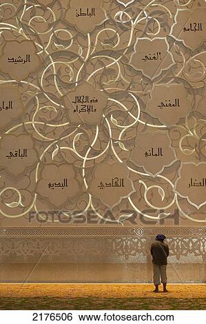 Stock Photograph - UAE, Man praying in front of Qibla wall in Sheikh Zayed Grand Mosque; Abu Dhabi. Fotosearch