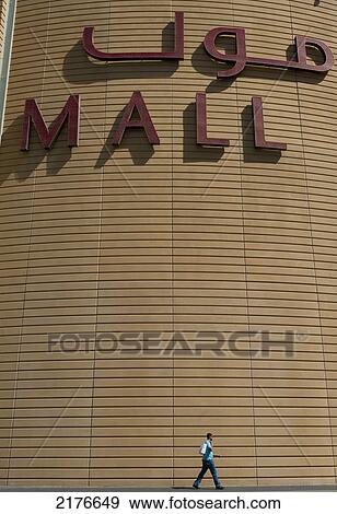 UAE, Man walking past large sign for the Dubai Mall; Dubai View Large Photo Image Stock Photo - UAE, Man walking past large sign for the Dubai Mall; Dubai. Fotosearch