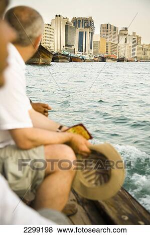 Stock Photo - UAE, Tourists riding small ferry on Dubai Creek; Dubai. Fotosearch