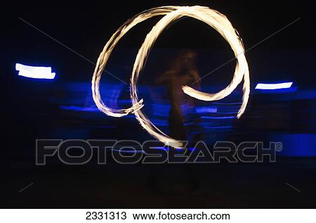 Stock Image - UK, Berkshire, Man juggling fire at night; Reading. Fotosearch
