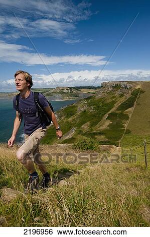 Stock Photograph - UK, Dorset, Walker going up stairs up to St Aldhelm's Head on South West Coastal Path; Purbeck. Fotosearch