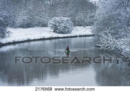 Stock Photo - UK, East Sussex, Canoeist going down River Ouse in snowy conditions; Lewes. Fotosearch