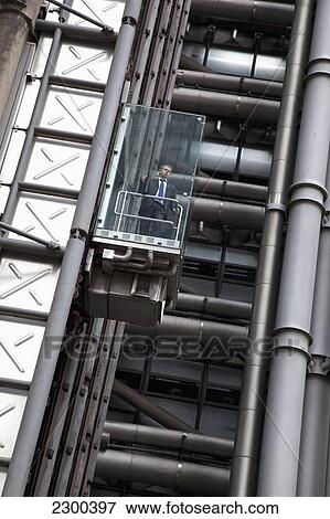 Stock Photo - UK, England, City worker in lift on exterior of Lloyd's Building; London. Fotosearch