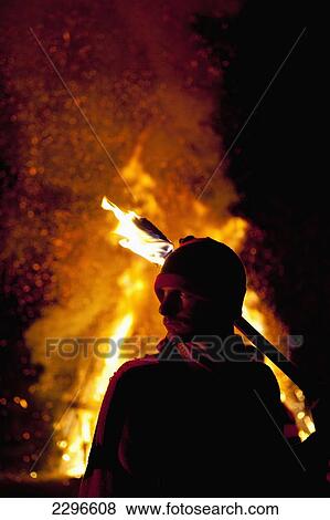 Stock Photo - UK, England, East Sussex, Newick Bonfire night; Newick, Man with burning torch standing in front of large bonfire. Fotosearch