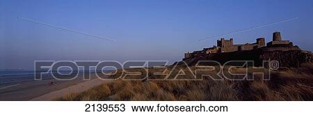 Stock Image - Uk, England, Northumberland, Northumbrian Coast, Panoramic View Of Sunset Over Bamburgh Castle And Beach; Bamburgh. Fotosearch