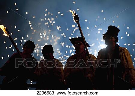 Stock Image - UK, England, People dressed as clergy on stand with fireworks behind them at Newick bonfire night; East Sussex. Fotosearch