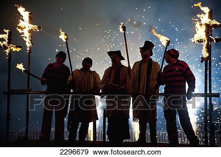 Stock Photo - UK, England, People dressed as clergy on stand with fireworks behind them at Newick bonfire night; East Sussex. Fotosearch