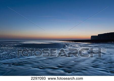 Stock Image - UK, England, River going out to sea at low tide at Cuckmere Haven at dusk; East Sussex. Fotosearch