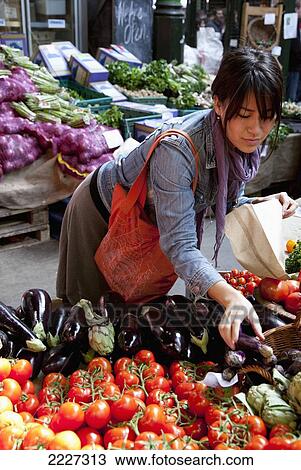 Stock Image - UK, England, Young woman shopping at Borough Market; London. Fotosearch