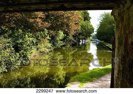 Stock Photo - UK., Hertfordshire, and lush green surrounding countryside. viewed from under a bridge; Hemel Hempstead, barges, towpath, The Grand Union Canal. Fotosearch