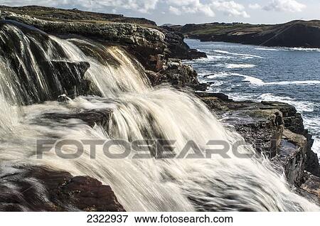Stock Photo - UK, Ireland, County Kerry, Cahersiveen, Peat colored water pouring into Cooncrome Harbor. Fotosearch