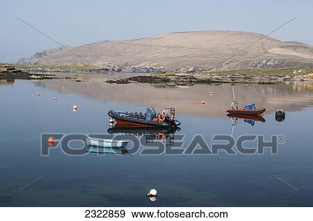 Stock Photo - UK, Ireland, County Kerry, Iveragh Peninsula, Portmagee, Boats mooring in tranquil water. Fotosearch