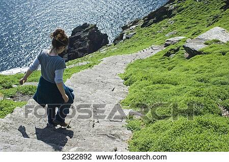 Stock Image - UK, Ireland, County Kerry, Skellig Islands, Hiker on footpath climbing up Skellig Michael. Fotosearch
