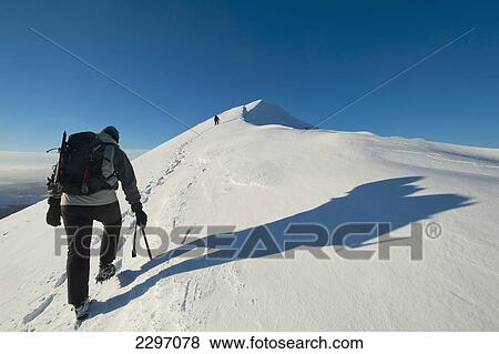 Stock Photo - UK, Man climbing snowy slopes of Sgorr Dhearg near Glen Coe (Glencoe) in Highlands; Scotland. Fotosearch