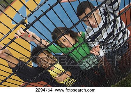 UK, Mixed group of teenagers behind iron railings at sports court; Hastings View Large Photo Image Picture - UK, Mixed group of teenagers behind iron railings at sports court; Hastings. Fotosearch