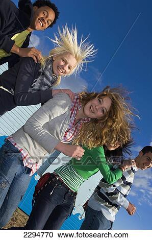 Stock Image - UK, Mixed group of teenagers dancing conga at seaside; Hastings. Fotosearch