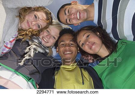 Stock Image - UK, Mixed group of teenagers huddled together; Hastings. Fotosearch