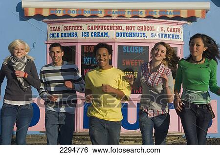 Stock Photograph - UK, Mixed group of teenagers running towards the camera in row at funfair; Hastings. Fotosearch