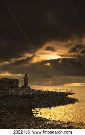 Stock Photograph - UK, Scotland, Dumfries and Galloway, Portpatric, Lighthouse on coast with stormy clouds. Fotosearch