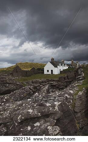 Picture - UK, Scotland, Highlands, Applecross Peninsula, Stone wall and cottage houses under stormy sky. Fotosearch
