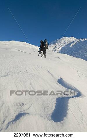 Stock Image - UK, Scotland, Man going through snow up Beinn Respiol on Ardnamurchan peninsula; Highlands. Fotosearch