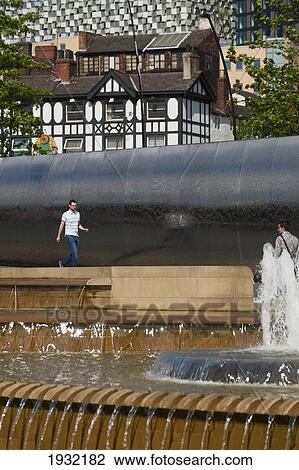 Stock Image - UK, South Yorkshire, Man walking near fountain; Sheffield. Fotosearch