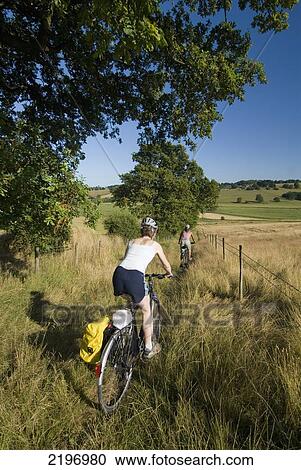 Stock Image - UK, Two women cycling down bridleway near Winchelsea; East Sussex. Fotosearch