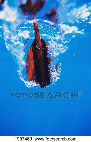 Stock Photo - Underwater View Of Wooden Paddle Stroking Water, Creating Bubbles.. Fotosearch