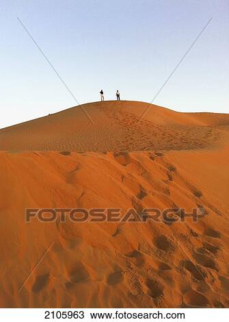 Stock Image - United Arab Emirates, Abu Dahbi, Empty Quarter, Liwa desert dune, Two people on top of sand dune. Fotosearch