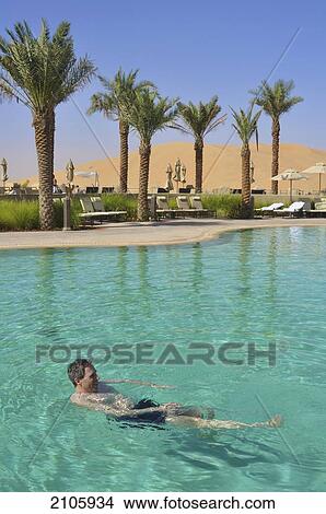 Picture - United Arab Emirates, Abu Dahbi, Qasr al Sarab, Tourist swimming in pool and dunes. Fotosearch