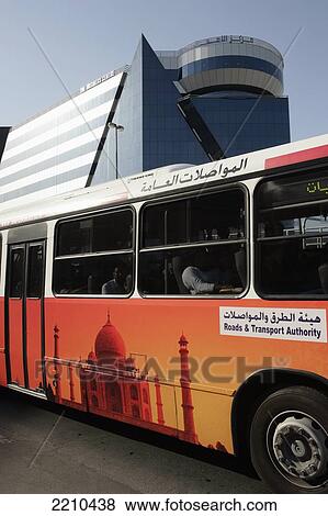 Stock Photo - United Arab Emirates, Bus With Mosque Depicted On The Side In Front Of Modern Building; Dubai. Fotosearch
