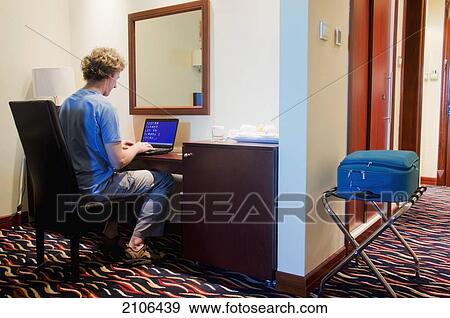 Stock Photo - United Arab Emirates, Man working on laptop in hotel room; Dubai. Fotosearch