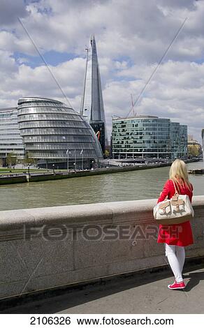 Stock Photograph - United Kingdom, City of London with Shard building in background; London, Woman standing at promenade. Fotosearch