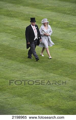 Stock Photography - United Kingdom, England, Couple Passing Grass; Berkshire, Royal Ascot Horse Racing. Fotosearch
