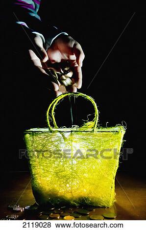 Stock Photo - United Kingdom, England, Money poured into yellow basket; Esher. Fotosearch