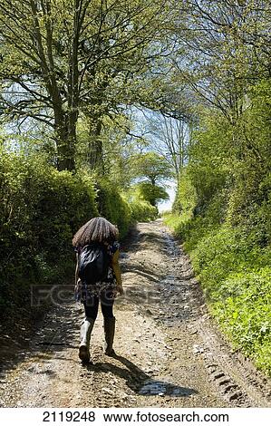 Stock Photo - United Kingdom, England, Rear view of woman walking in countryside; Devon. Fotosearch
