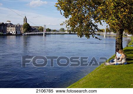 Stock Photography - United Kingdom, Man and woman sitting next to river; Scotland. Fotosearch